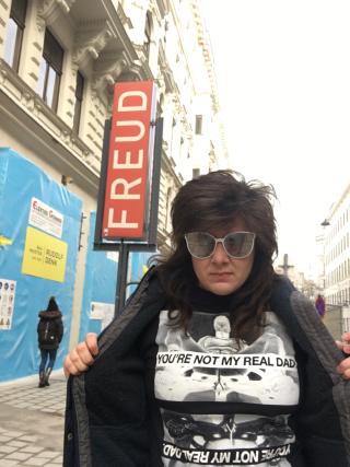 Carrie Rennolds opoens her coat, wearing a shirt that says &ldquo;You&rsquo;re not my Dad&rdquo;. The Freud museum is in the background.